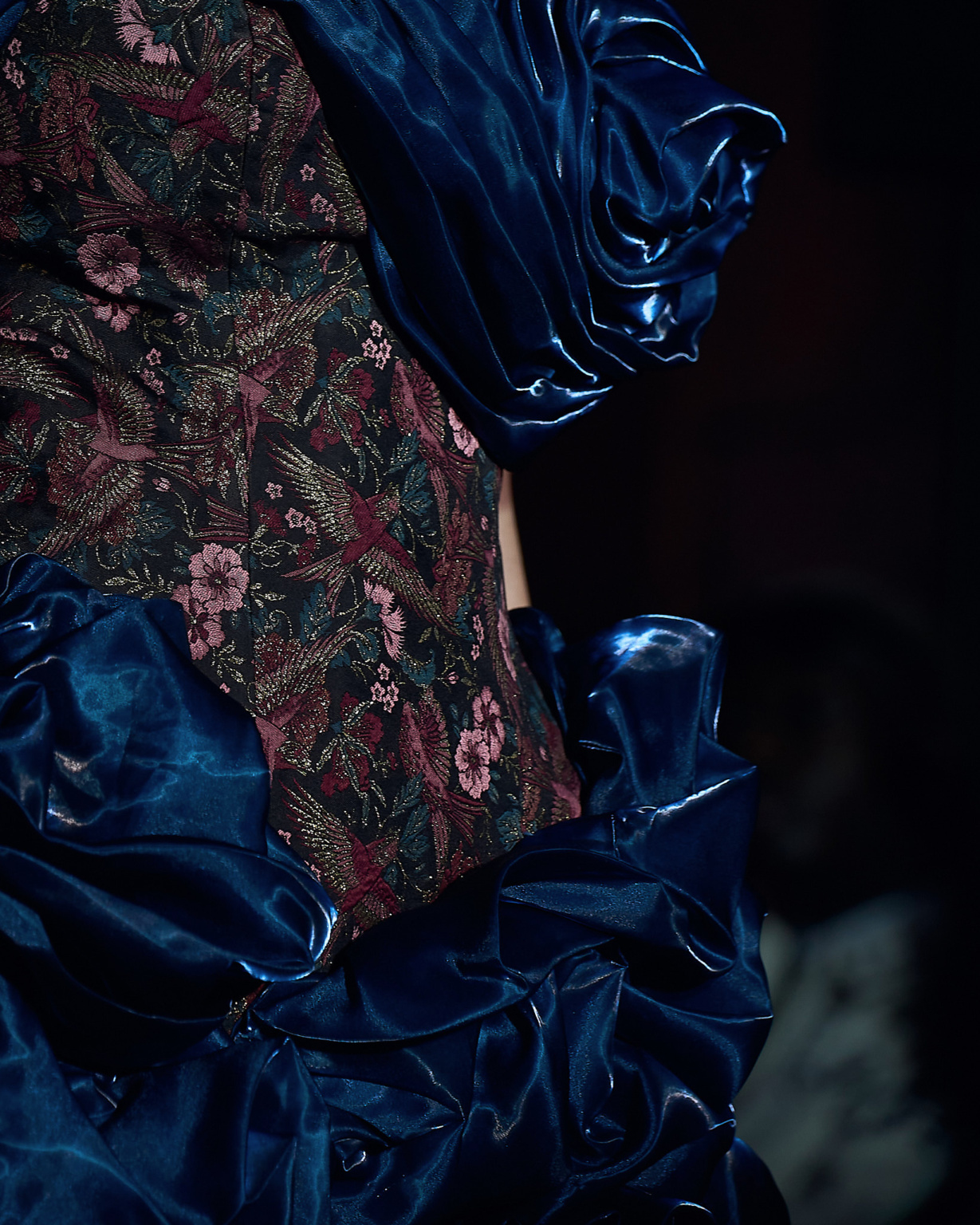 Fashion detail shot, sculptural royal blue satin gown with floral brocade corset, dramatic low lighting