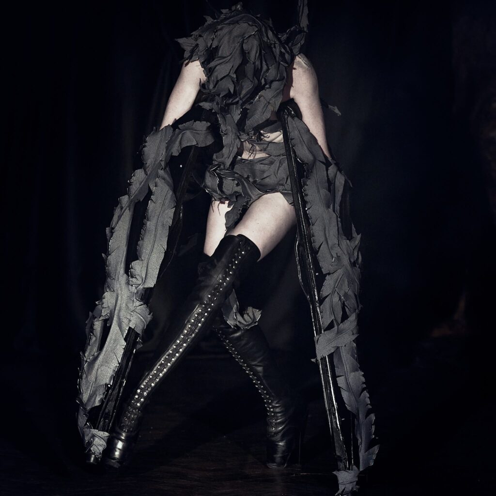 Fashion show, LFW AW26 Silvercity, model wearing long platform boots, dark moody lighting