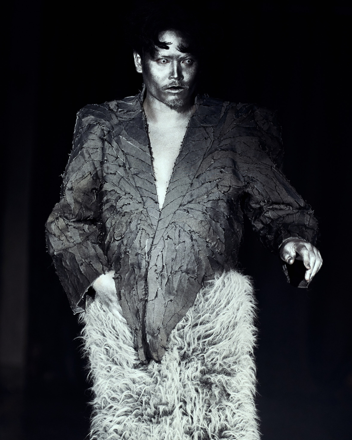 Fashion show, LFW AW26 Silvercity, model wearing grey jacket and fur trousers, dark moody lighting