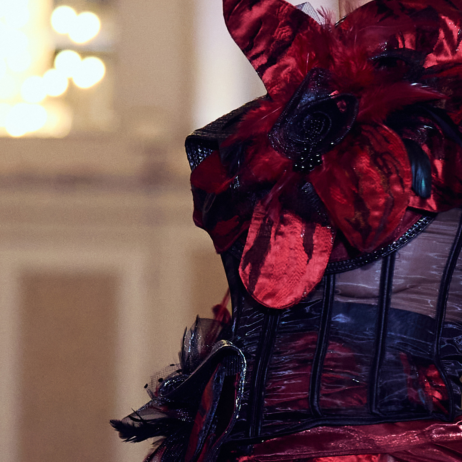 Detail shot, red gown and black corset decorate with flower pieces, runway lighting