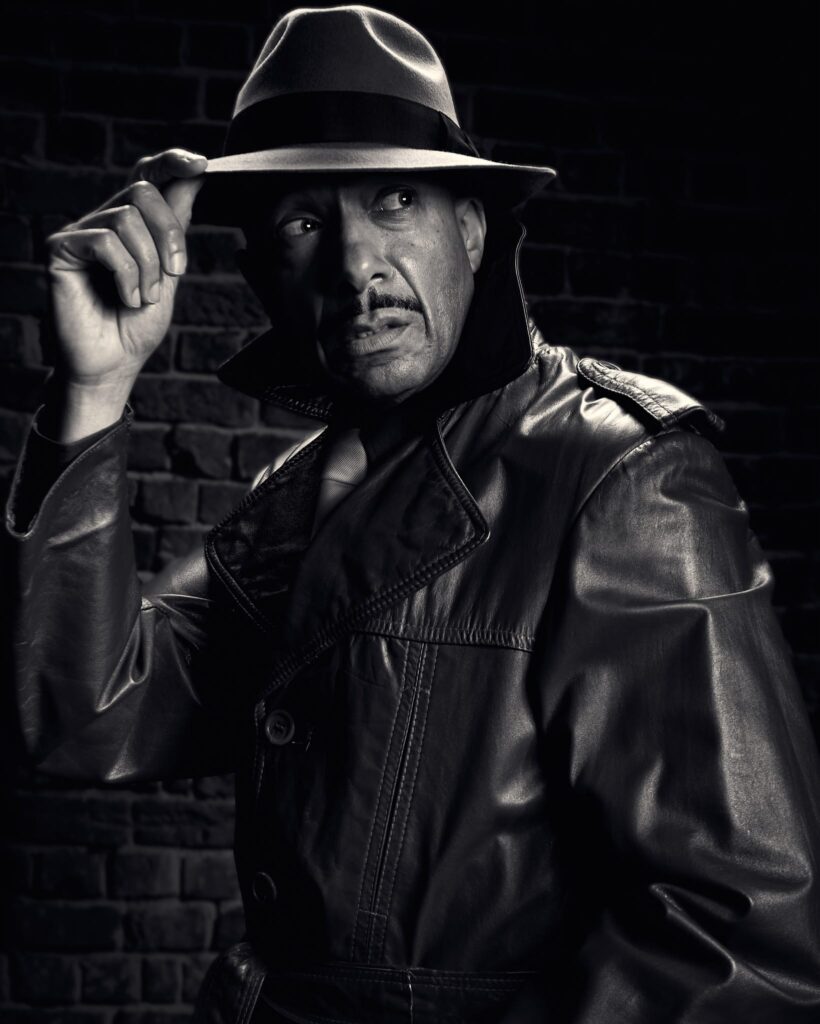 Fashion noir portrait, Sin City inspired, model wearing hat, a leather trench coat and a tie, dramatic noir lighting
