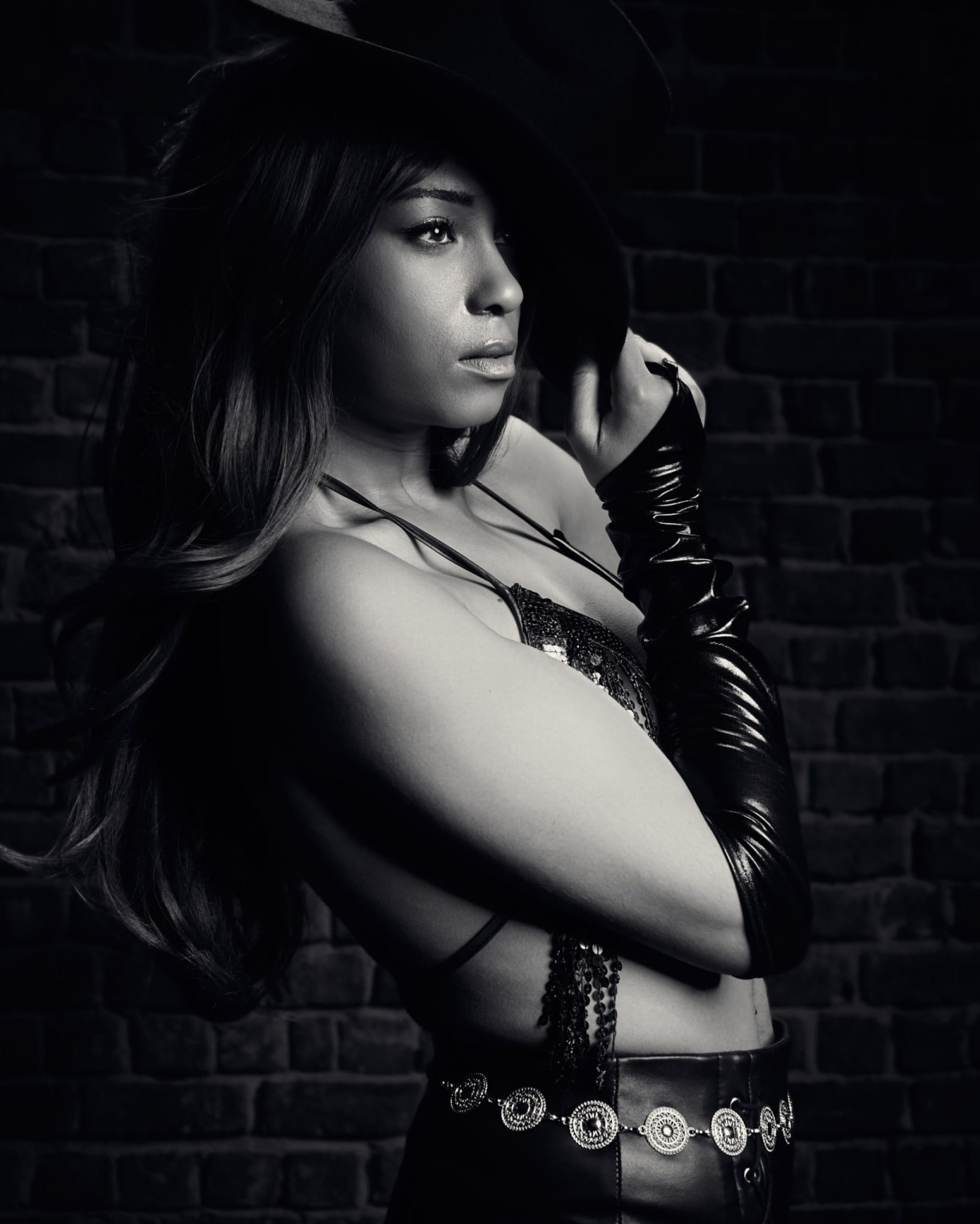 Fashion portrait, Sin City inspired, model wearing hat, vinyl gloves and leather trousers with silver belt, dramatic chiaroscuro high contrast lighting